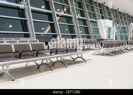 Clean airport terminal interior with empty waiting seats and large glass windows. Travel background with copy space for tourism, transportation, busin Stock Photo