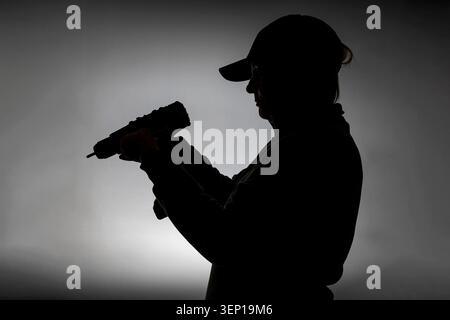 A woman is holding a cordless drill against the light Stock Photo