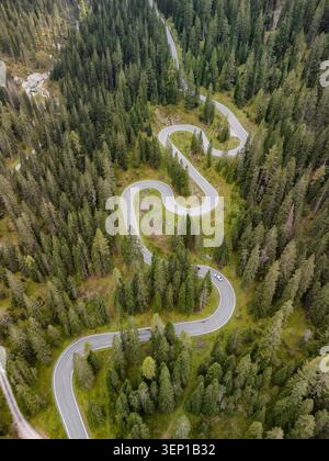 Aerial view of a winding serpentine road cutting through the lush green ...