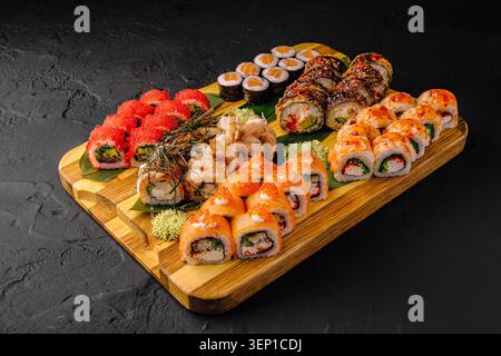 Various sushi rolls are arranged neatly on a wooden board. The plate shows different types of sushi with vibrant colors. This is a common scene in a restaurant during the evening. Stock Photo