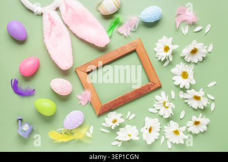 Easter background with white chrysanthemums flowers, colored eggs and decorations on color background with frame. Top view. Flat lay Stock Photo