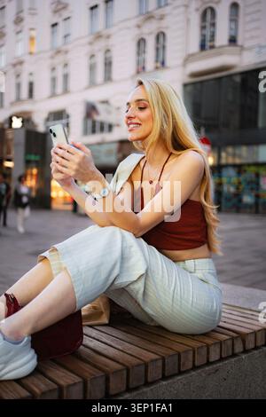 Young woman smiling texting on mobile phone in European city Stock Photo