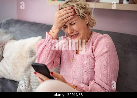 Woman holding head crying receiving bad news on phone Stock Photo