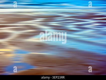 Abstract long-exposure beach scene showing water reflections and motion blur across wet sand. Stock Photo