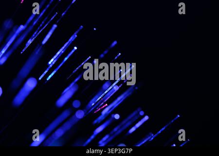 Bright blue optical fiber ends gathered in corner against solid black abstract space Stock Photo