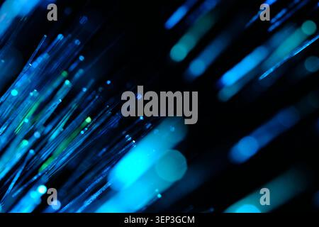 Vibrant blue and cyan optical fibers shining brightly diagonally across black background Stock Photo