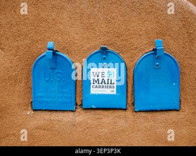 Santa Fe, NM - May 6 , 2026 - Three blue antique mailboxes inset on an adobe wall make an abstract composition Stock Photo