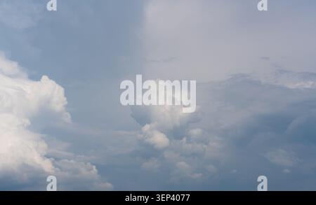 Soft clouds drift above a calm, pale blue sky Stock Photo