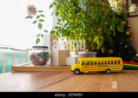 School bus toy on wooden desk with calculator notebooks markers and paper clips for back to school theme math learning classroom supplies homeschool Stock Photo