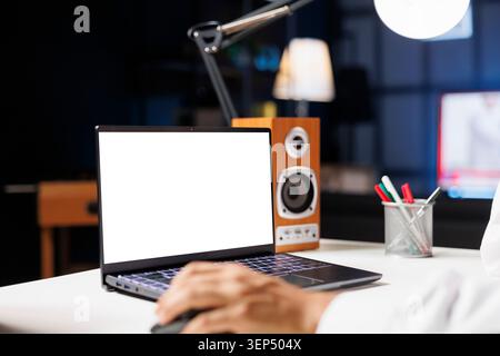 Muslim man sits at his home workstation, his computer monitor displaying an isolated chromakey template. Young Arab man working on a desktop computer with a copyspace white screen. Stock Photo