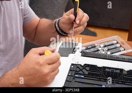 Man repairing electronics, focusing on disassembling a device with tools Stock Photo