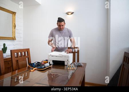 Man repairing a printer on a table, highlighting home repair and maintenance Stock Photo