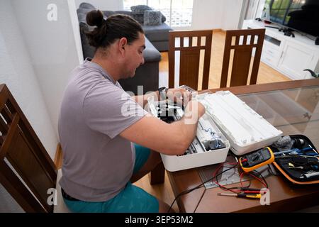 Man repairing electronics, using tools and multimeter on a printer at home Stock Photo