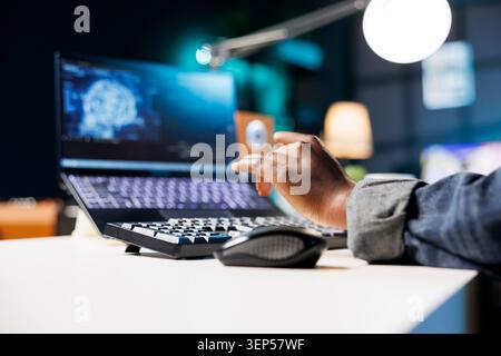 African American individual using bluetooth keyboard for typing, computing code for creating databases. Close up of black person working from home, monitoring software system and data center. Stock Photo