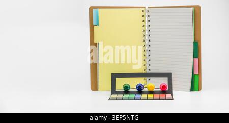 Open spiral notebook with colorful sticky flags and push pins, creating a creative workspace for planning, studying, and organizing ideas on a clean w Stock Photo