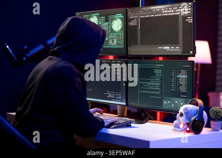 Hacker typing on PC keyboard, using malicious spyware program in a cybersecurity concept. Stock Photo