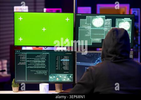 Hacker doing phishing attacks using green screen PC, tricking users into revealing credit card data while man launching DDoS attacks with mockup computer, flooding servers to crash websites. Stock Photo