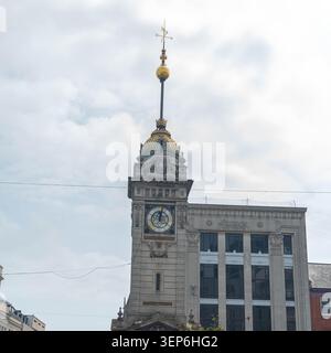 A clock tower is visible with a gold dome and a large clock face. The tower is part of a building in the city. The sky is cloudy and gray, showing a t Stock Photo