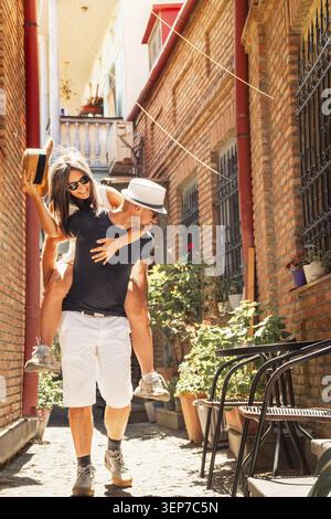 Joyful middle aged couple friends having fun together enjoying vacation on old city street.Carefree married couple in love having fun enjoying time to Stock Photo