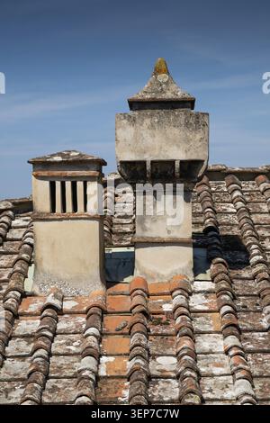 Two old chimneys on a weathered tiled roof under a blue sky, outbuilding of the Medici Renaissance villa Poggio a Caiano, built from 1485 by Lorenzo i Stock Photo