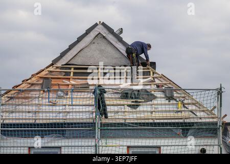 Carpenter on house roof, energy-efficient renovation of an apartment building, renovation of an old building, thermal insulation, new windows, new roo Stock Photo