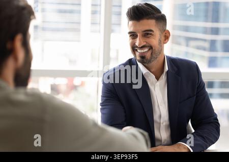Cheerful Indian businessman greeting corporate client with handshake Stock Photo