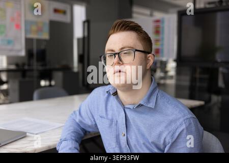 Young man with Down syndrome in modern office Stock Photo