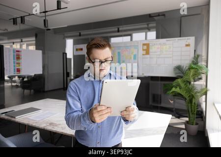 Young man with Down syndrome using tablet in office Stock Photo