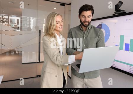 Coworkers analyzing business data on laptop in workspace Stock Photo