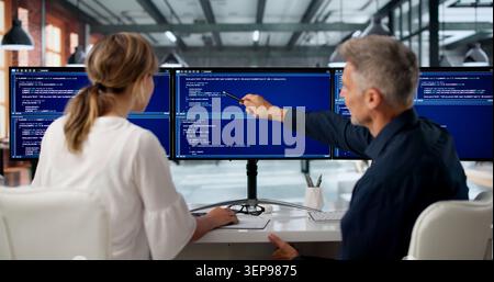 Two Software Engineers Work Side By Side Coding Secure Web Applications Together. Stock Photo