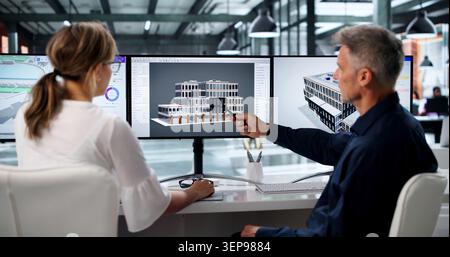 Two Engineers Discuss 3D Building Plans Using BIM Software On Screen. Stock Photo