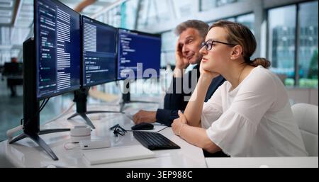 Frustrated Developers Face Coding Mistakes While Working Late In Quiet Office. Stock Photo