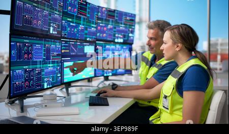 Two Engineers Monitor Multiple Screens Controlling Oil Plant Systems. Stock Photo
