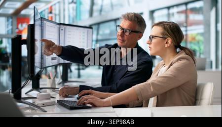 Two Office Workers Analyze Digital Document Workflow System On Computer Screen. Stock Photo