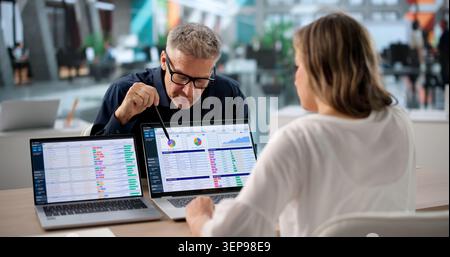 Woman And Man Reviewing Medical Billing Data On Laptop In Office. Stock Photo