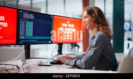 Experienced Cybersecurity Analyst Monitors Malware Threats On Multiple Computer Screens. Stock Photo