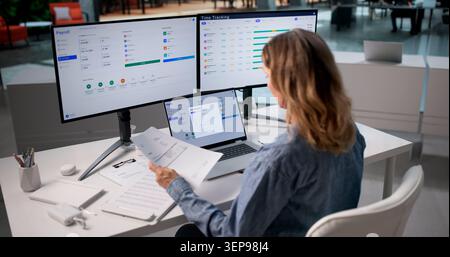 Mature Woman Uses Laptop And Calculator To Review Payroll Data. Stock Photo