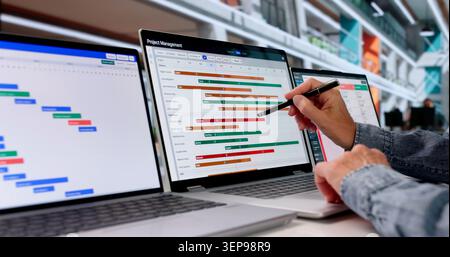 Experienced Project Manager Updates Agile Task Board On Laptop At Office. Stock Photo
