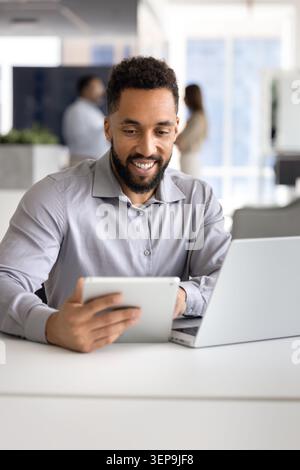 Smiling businessman using tablet at modern office desk Stock Photo