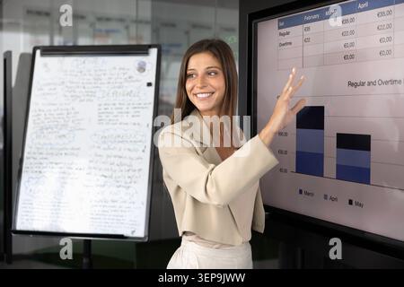 Smiling Argentinian businesswoman presenting data on screen Stock Photo