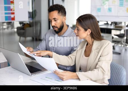 Coworkers analyzing documents seated at office desk Stock Photo