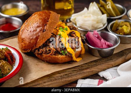 Slow cooked pulled rib beef burger with melted cheese and sides Stock Photo