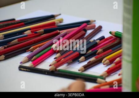 Assortment of vibrant colored pencils scattered on a white piece of paper during a creative activity in Ciego de Ávila Stock Photo