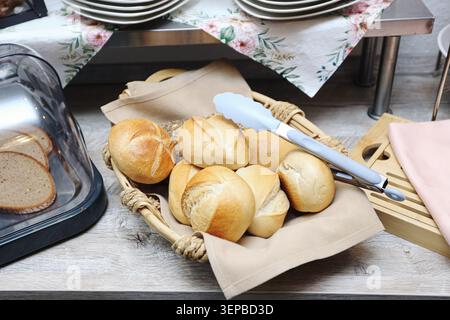 Fresh bread rolls served in basket on dining table. Traditional bakery products prepared for breakfast and family meals at home. Stock Photo