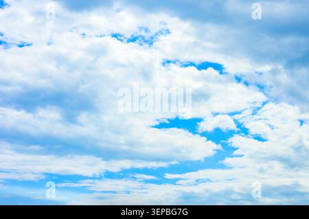 Wispy, textured white clouds drifting slowly across a deep blue sky, creating a peaceful and serene atmosphere Stock Photo