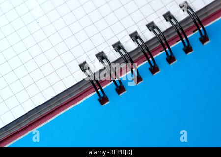 A checkered notebook lies open on a vibrant blue surface, waiting for creativity. Stock Photo