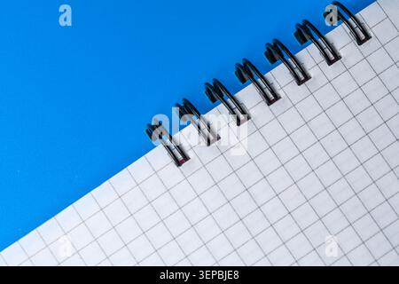A blank grid notebook lies open, inviting ideas on a vibrant blue surface. Stock Photo