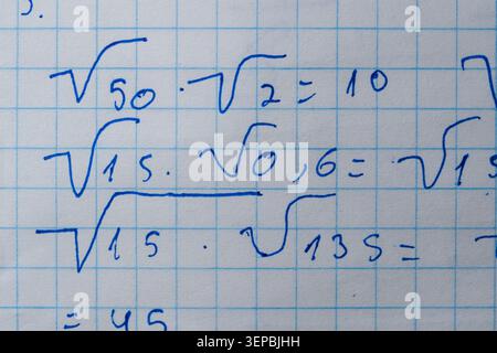 Notes filled with square roots and equations fill a grid paper, showcasing learning. Stock Photo