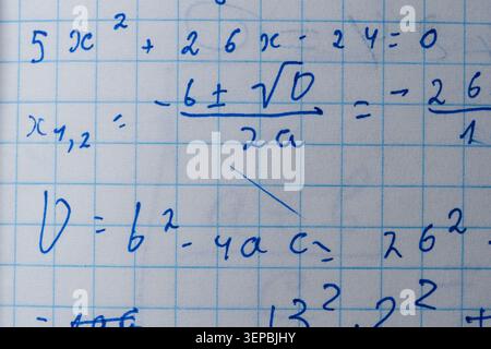 Notes show steps to solve quadratic equations in a cozy classroom setting. Stock Photo