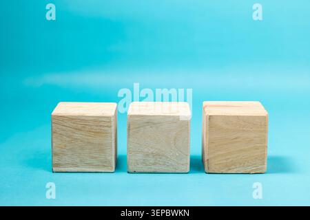 A row of three blank wooden blocks with small spaces between them, isolated on a bright cyan blue backdrop, perfect for copy space or adding three-letter words. High Quality Photo Stock Photo